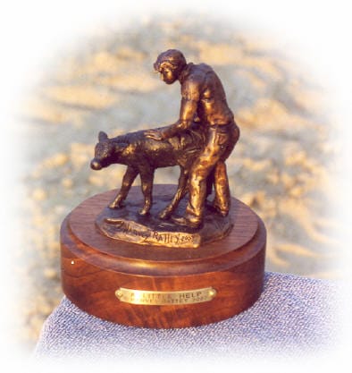 Bronze sculpture of boy helping newborn calf.
