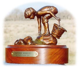 Bronze sculpture of a little boy holding a pail, catching minnows in the creek.