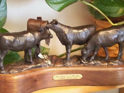 Bronze sculpture of three Angus heifers checking a mailbox.