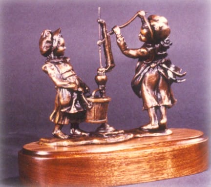 Bronze sculpture of pioneer girls hand pumping water.