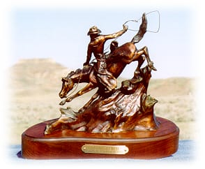 Cowboy running his horse down a hill and roping.