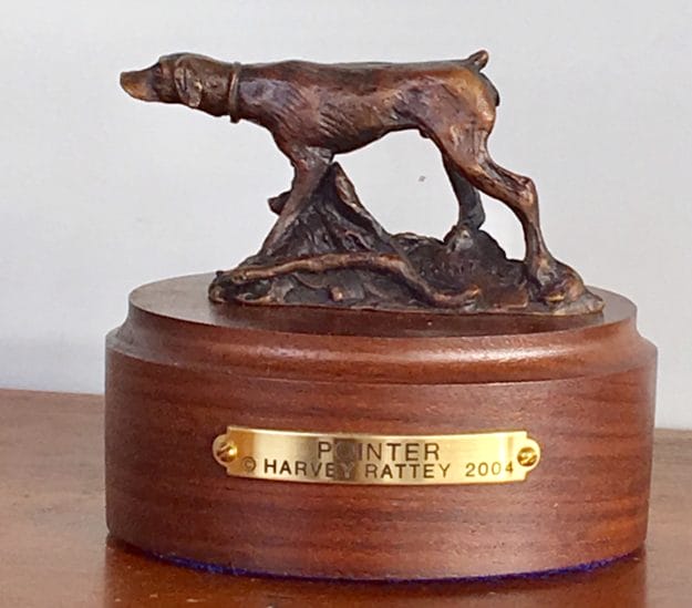 Bronze sculpture of hunting dog pointing at game.