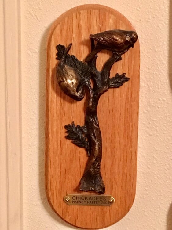 Small bronze sculpture of a cedar waxwing on a branch.