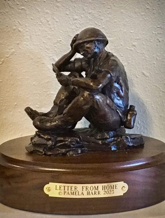 bronze sculpture of a soldier reading a letter from home.